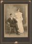 Photograph: [Photograph of a Seated Man and Standing Woman]