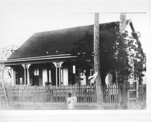 Primary view of [Photograph of a girl holding a little boy in front of the Adams house]