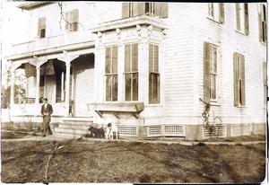[Man and two dogs in front of house]