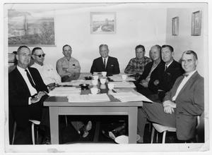 Eight Men sitting at table for a school board meeting