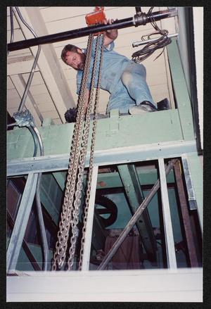 [Photograph of Joe Cavanaugh Kneeling on Machinery in the Dr. Pepper Museum]