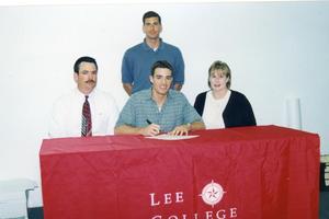 Primary view of object titled 'Aaron Woodard signs a scholarship agreement to play basketball for Lee College, on hand for the signing are parents, seated, Tommy Woodard and Melanie Baily, along with Roy Champage, standing , Lee College basketball coach.'.