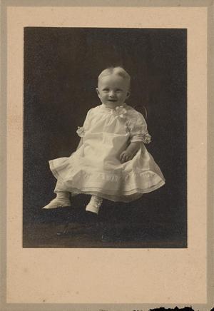 [Portrait of a Smiling Child in a Metal Chair]