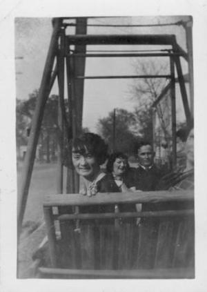 [a group of four people seated on a double wooden swing.]