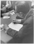 Photograph: Instructor Signing Papers at His Desk