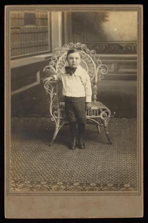 [Portrait of an Unknown Boy Next to a Wicker Chair]