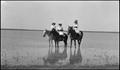 Photograph: [Three young women on horseback at the edge of a playa lake]