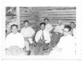 Photograph: [Group of Hispanic Men Sitting in a Log Cabin]