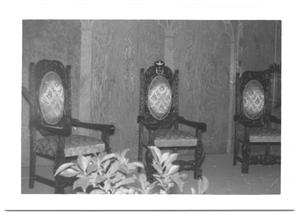 [Three Carved Chairs Against a Wood-grain Wall]