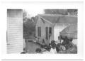 Photograph: [People Lined Up Outside of a House]