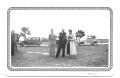 Primary view of [Three People Standing in a Field with Cars]