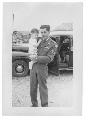 [Henry Camacho in a Uniform Holding a Baby]
