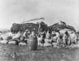 Photograph: [People Resting on Sacks Filled With Rice After Harvesting]