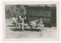 Photograph: [Soldiers Lounge Outside a Hut]