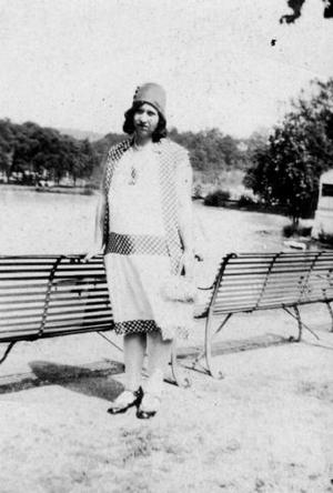 [Photograph of Woman Standing in Front of Park Benches]