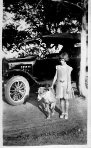 [Unidentified girl and dog in front of an automobile]