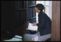 Photograph: [Man Looks Through a Bookshelf at the Dr. Eugene Clark Public Library]