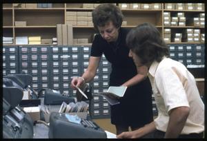 [Librarian Virginia Kuse Helps Man Look Through Card Catalog in an Office Space]