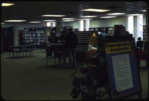 [Library Interior with Community Analysis Sign]