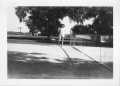 Photograph: [Woman standing by a net at Booth Tennis Courts]