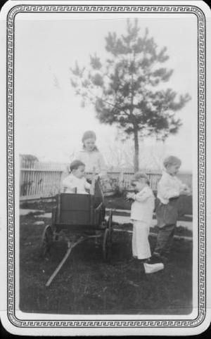 [Children standing around a child in a wagon at Mary Dee and August Myers home]
