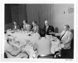 Primary view of [Lamar Fleming Jr. seated at formal breakfast with unidentified men]