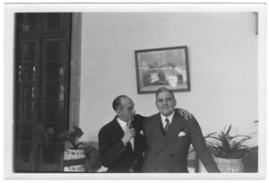 [George Alfred Hill, Jr. with unidentified man in room with potted plants]