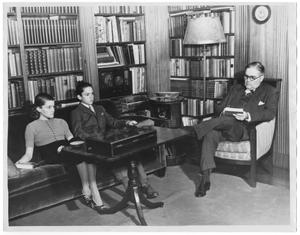 Primary view of object titled '[George A. Hill, Jr. and children with bookshelves and lamp in background]'.