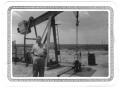 Thumbnail image of item number 1 in: '[Lamar Fleming, Jr. posed in front of oil well with sign L. F. Oil Co.]'.