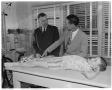 Primary view of [Two men standing next to boy on examination table]