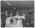 Thumbnail image of item number 1 in: '[Four men wearing suits, standing behind a display for National Flower Week]'.