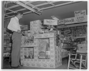 Primary view of object titled '[A man standing next to a Jax display at 7-11]'.