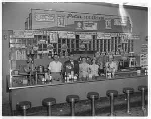 Primary view of object titled '[People standing behind the counter of an ice cream parlor]'.