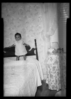 [Photograph of a Young Child Standing on a Bed]