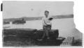 Photograph: [Man Sitting on Wooden Wall]
