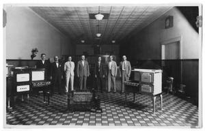 Primary view of object titled '[Men Standing With Gas Ranges and Fireplace]'.