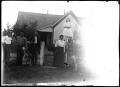 Photograph: [Group posed in front of a home with dogs]