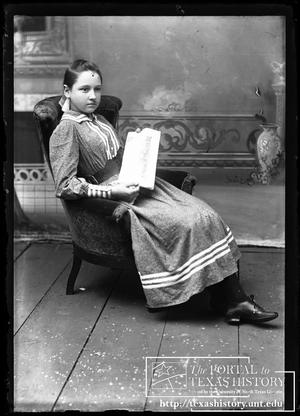 [Girl sitting in a chair holding the "Youth's Companion" magazine]
