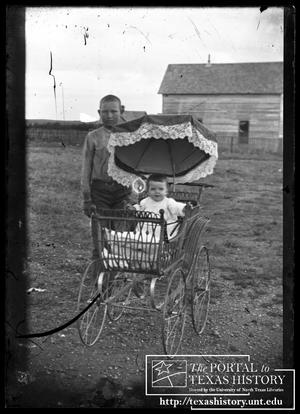 [Boy and a baby in a wicker baby carriage]