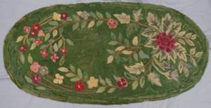 Green rug with red, pink, and green floral design.