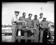 Photograph: [Men viewing machine parts in front of Denton police car]