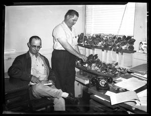 [Two unidentified men in office with African violets]