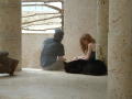 Primary view of [Young couple sit inside a stone structure, near a window]