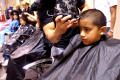 Photograph: [Children have their hair cut at a back to school fair]