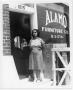 Photograph: [Woman in front of Alamo Furniture Company shop]