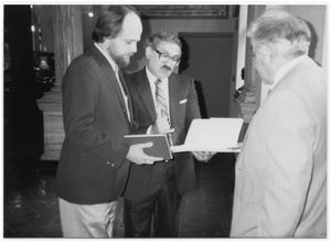 Primary view of object titled '[Tom Kreneck and two men looking at materials]'.