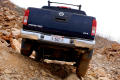 Primary view of [Back of a Nissan Frontier truck driving down a rocky slope]