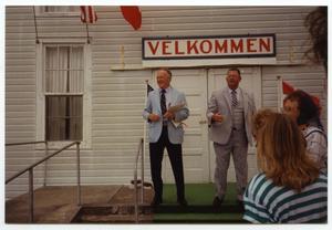 Primary view of object titled '[Two Men in front of Velkommen Sign]'.