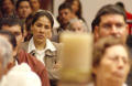 Primary view of [Woman listens to the priest along with the rest of the congregation]