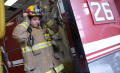 Thumbnail image of item number 1 in: '[A fireman puts on his fire-fighting gear beside fire engine #26]'.